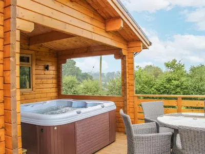 a hot tub on a deck with a table and chairs at Manor Farm Lodges - Red Kite Lodge in Newtown