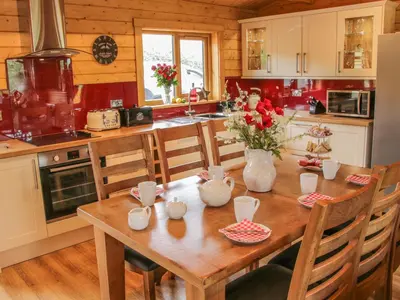 a kitchen with a wooden table with flowers on it at Manor Farm Lodges - Dragon Lodge in Newtown