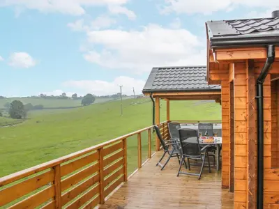 a wooden deck with a table and chairs on it at Manor Farm Lodges - Dragon Lodge in Newtown