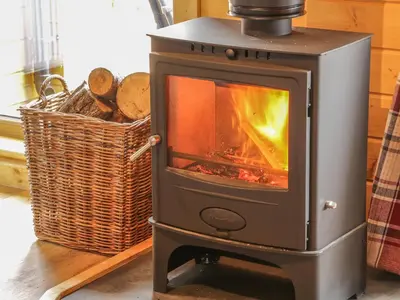 a wood stove sitting next to a basket of logs at Manor Farm Lodges - Dragon Lodge in Newtown