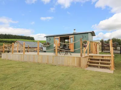a tiny house with a deck and a fence at Ivy's Way in Rhayader