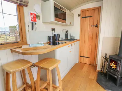 a kitchen with a stove and two stools in a tiny house at Ivy's Way in Rhayader
