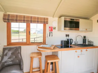 a kitchen with a sink and a counter with stools at Ivy's Way in Rhayader