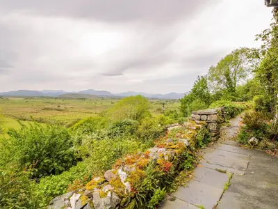 a stone wall and a field with mountains in the background at Llety Perygl in Harlech
