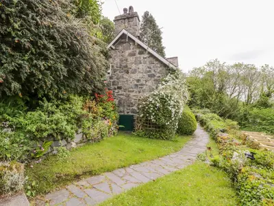 an old stone house with a garden and a path at Llety Perygl in Harlech