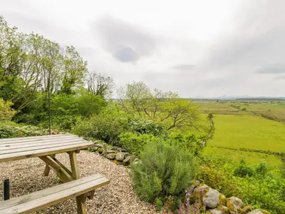 a wooden bench sitting on top of a field at Llety Perygl in Harlech
