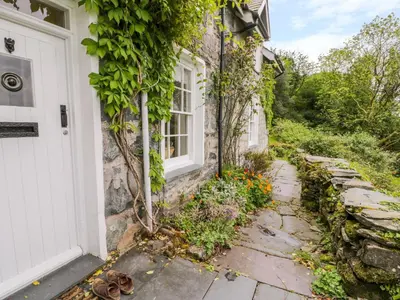 a stone house with a white door and a walkway at Llety Perygl in Harlech