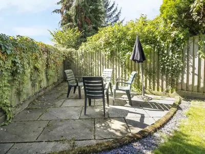 a patio with chairs and an umbrella next to a fence at Ty'r Orsaf in Builth Wells