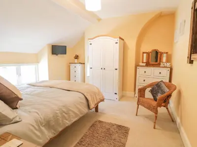 a bedroom with a bed and a chair at Angorfa in Llanbedr