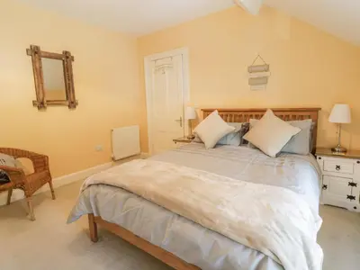 a bedroom with a large bed and a chair at Angorfa in Llanbedr