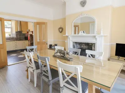 a dining room with a table and chairs and a fireplace at Angorfa in Llanbedr