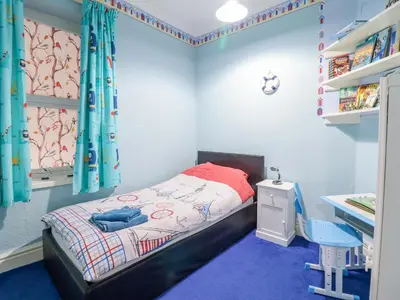 a small bedroom with a bed and a desk at Minydon in Fairbourne