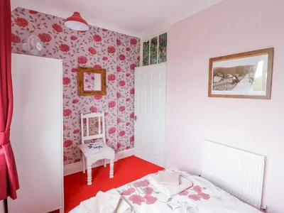 a bedroom with pink floral wallpaper and two beds at Minydon in Fairbourne