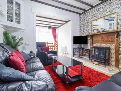 a living room with a leather couch and a fireplace at Minydon in Fairbourne