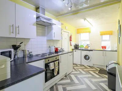 a kitchen with white cabinets and a stove top oven at Minydon in Fairbourne