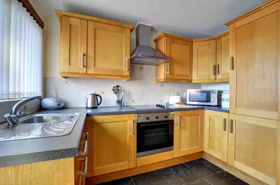 a kitchen with wooden cabinets and a sink at 2 Bed in Welshpool oc-wab256 in Berriew