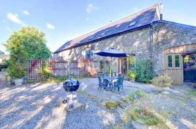 a stone house with a table and chairs and an umbrella at 2 Bed in Crugybar oc-waw323 in Llansawel