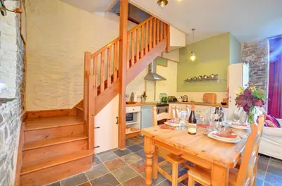 a kitchen and dining room with a wooden table and stairs at 2 Bed in Crugybar oc-waw324 in Llansawel