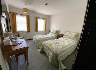 a hotel room with two beds and a table at The Griffin Llyswen in Brecon