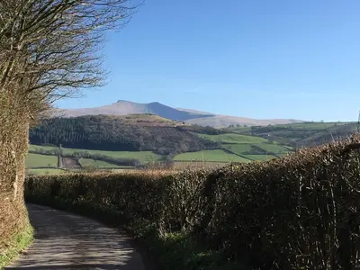 a dirt road with a mountain in the distance at Garden Room near Brecon in Brecon