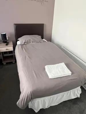 a bed with a white blanket and a night stand at Hampton Hotel & restaurant in Llandrindod Wells