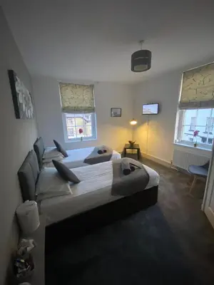 two beds in a room with two windows at The Swan Hotel in Kington