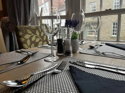 a table with glasses and silverware on a table with a window at The Swan Hotel in Kington