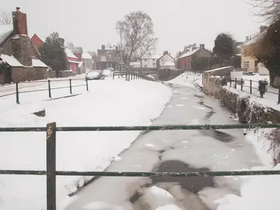 a street covered in snow with houses and cars at Penmaen in Talgarth