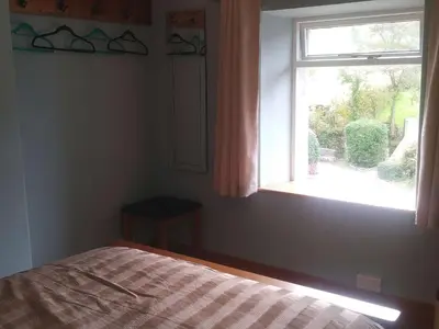 a bedroom with a bed and a window at Mill Cottage in Llanddeiniol