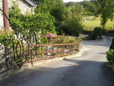 a fence with an umbrella on the side of a road at Mill Cottage in Llanddeiniol