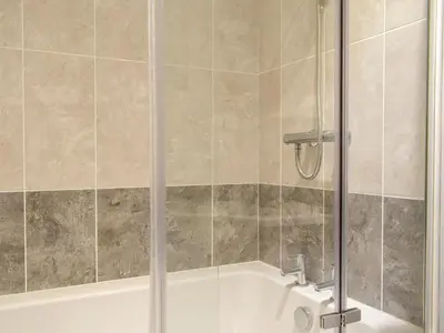 a shower with a glass door in a bathroom at Windhover in Glasbury