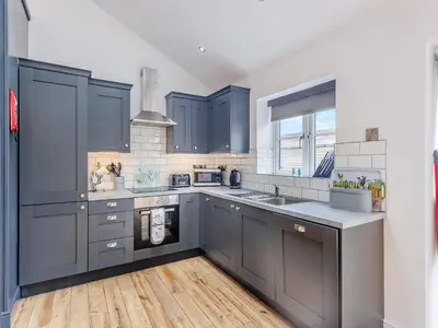 a kitchen with blue cabinets and a wooden floor at Ty Felin - Uk12744 in Acrefair