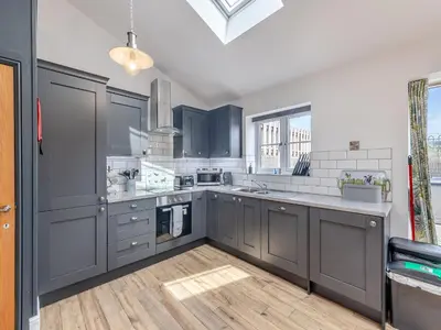 a kitchen with blue cabinets and a wooden floor at Y Stabl - Uk12742 in Acrefair