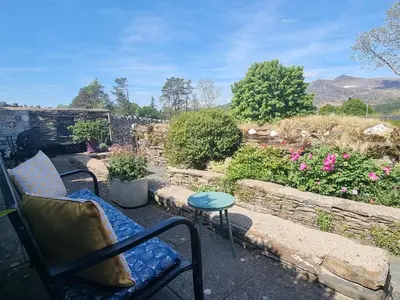 a patio with a bench and a table and flowers at Moelwyn View Cottage in Blaenau-Ffestiniog