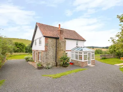 a house with a greenhouse on the side of it at The Old Farmhouse, Upper Pitts in Knighton