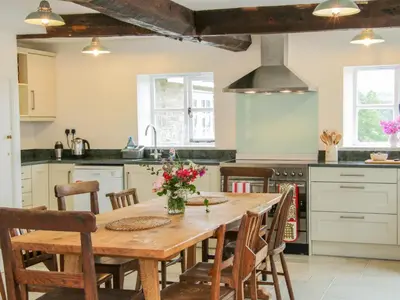 a kitchen with a wooden table and chairs at The Old Farmhouse, Upper Pitts in Knighton