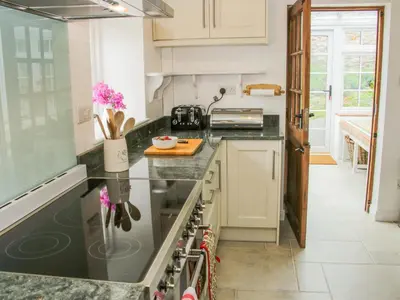 a kitchen with white cabinets and black counter tops at The Old Farmhouse, Upper Pitts in Knighton