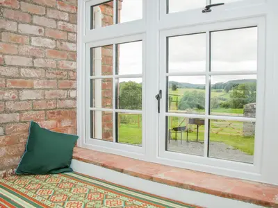 a window seat with a pillow and a brick wall at The Old Farmhouse, Upper Pitts in Knighton