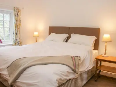 a bedroom with a large bed with white sheets and pillows at The Old Farmhouse, Upper Pitts in Knighton