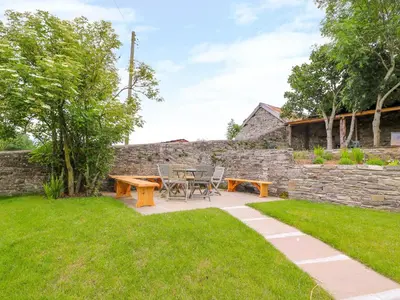 a patio with a table and chairs in a yard at The Old Farmhouse, Upper Pitts in Knighton