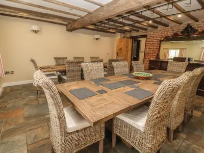 a dining room with a wooden table and chairs at Rhandregynwen Hall in Llanymynech