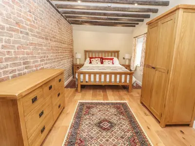 a bedroom with a bed and a brick wall at Rhandregynwen Hall in Llanymynech