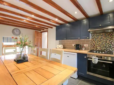 a kitchen with blue cabinets and a wooden table at Old Hall Barn 3 in Church Stretton