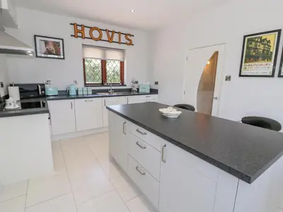 a kitchen with white cabinets and a black counter top at Berwyn in Talybont