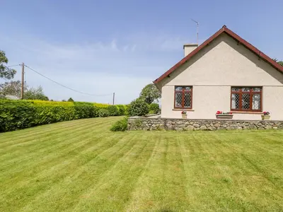 a small white house with a large yard at Berwyn in Talybont