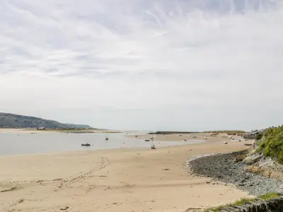 a sandy beach with people in the water at Abermaw Views in Barmouth