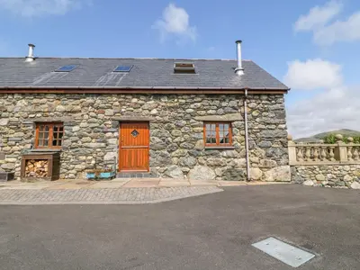 a stone building with a brown door and windows at Dysynni in Tywyn