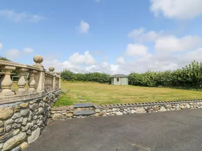 a stone fence with a field and a house in the background at Dysynni in Tywyn