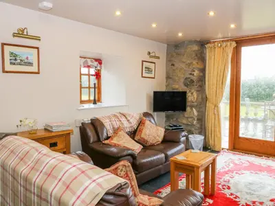a living room with a leather couch and a television at Dysynni in Tywyn