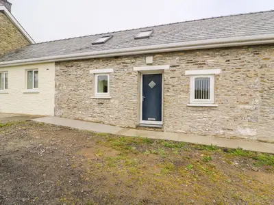 a stone house with a blue door and a yard at Hen Brynbedw in Llanybydder